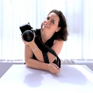 Fotografin mit Kamera in der Hand und hellem Hintergrund
