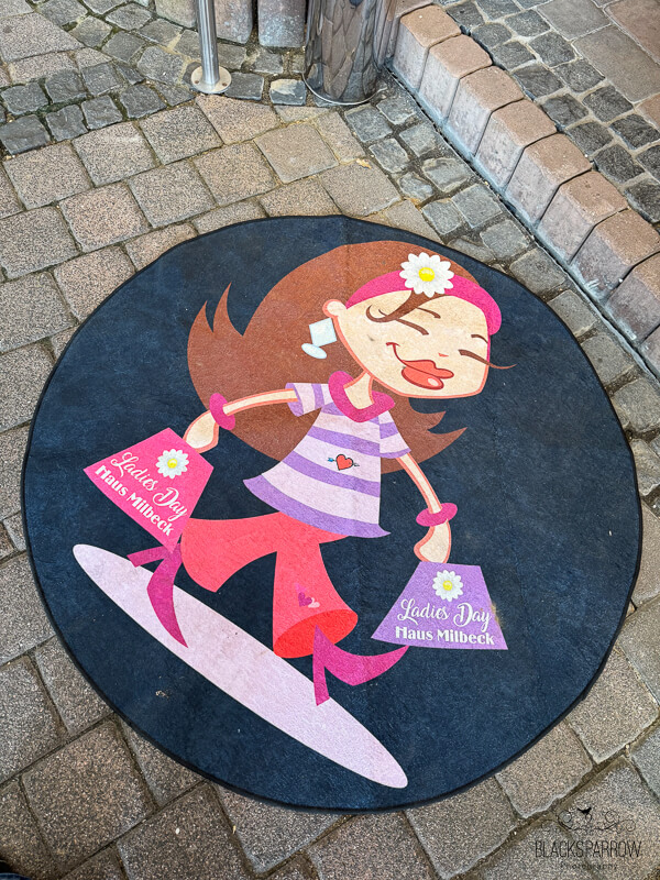 Teppich mit einer Illustration einer Frau mit Einkaufstaschen auf einem Ladies-Day- im Haus Milbeck in Hinsbeck.